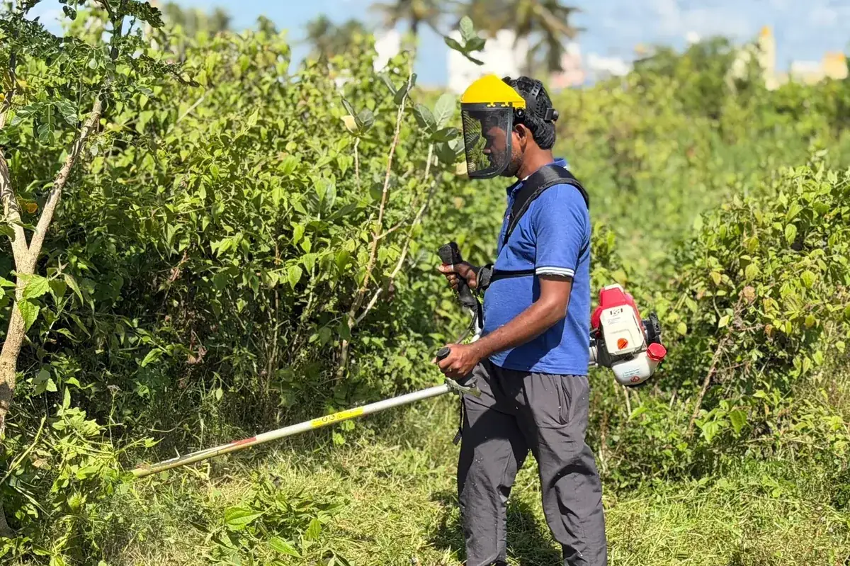 Operator in a yellow safety visor cutting into a dense bush line with the Rancher RXB45