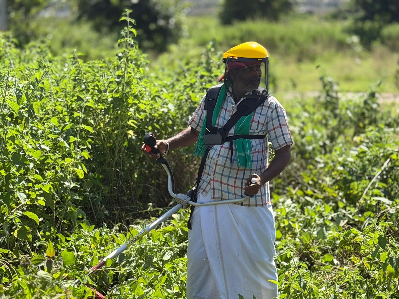 Farmer standing in waist-high weeds with the Rancher RXB45, wearing a yellow safety visor