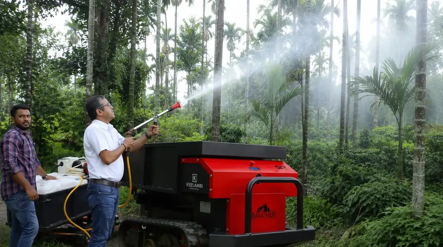 An operator spraying an arecanut canopy while the Rancher SEV 5.1 carries the tank